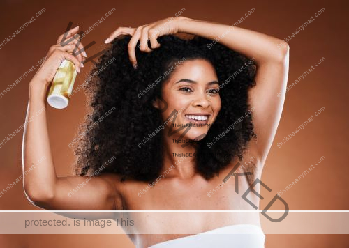 A black woman applying curly hair products to her long curly hair, smiling