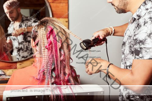 A hair crimper being used by a professional hair stylist to his client in a salon