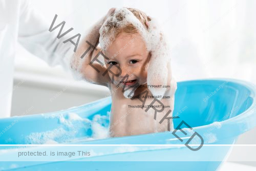 Baby having shampoo time in a blue baby tub