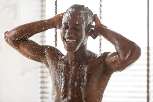 Black man with short curly hair enjoying a shower, shampoo, and bodywash