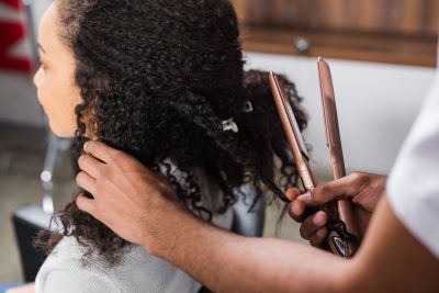 Black woman with very curly hair having a hair straightening session at the salon