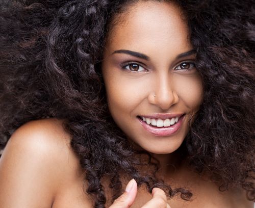 Close up shot of a black woman with very thick curly hair, like she would enjoy curly hair products