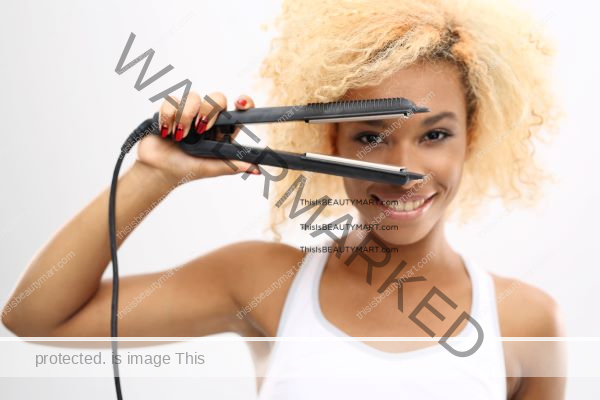 Hair straigthener flat iron playfully held by a black woman with blonde curly hair smiling