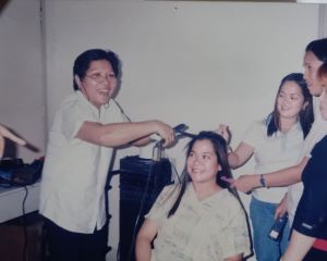 Mila, the veteran beauty cosmetics professional, while straightening her client's hair using a flat iron 