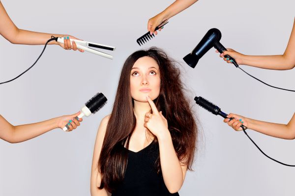 Various hair products and tools held around the bewildered face of a woman