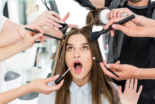 Woman receiving multiple cosmetics and beauty treatments at the salon and looking overwhelmed
