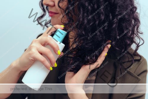 Woman, whose face is not seen, applying a curly hair product to her luscious curly locks