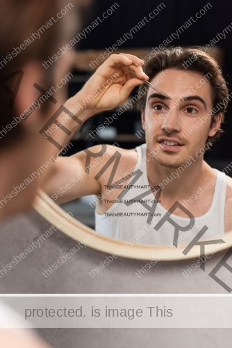 A man using tweezers to shape and groom his eyebrows