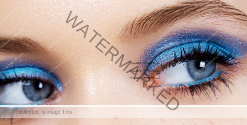 Close up of a woman's eye cosmetics in metallic blue eye shadow and long eye lashes