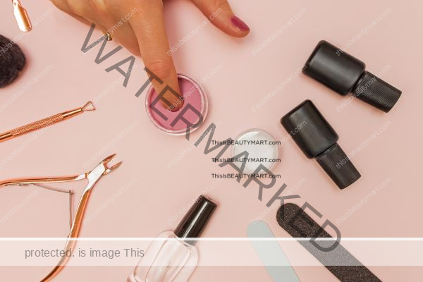 Nail in nail dip powder jar surrounded by nail tools kit