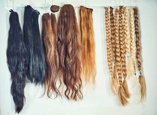 various hair extensions and braided hair weaves of various colors hung on a wall